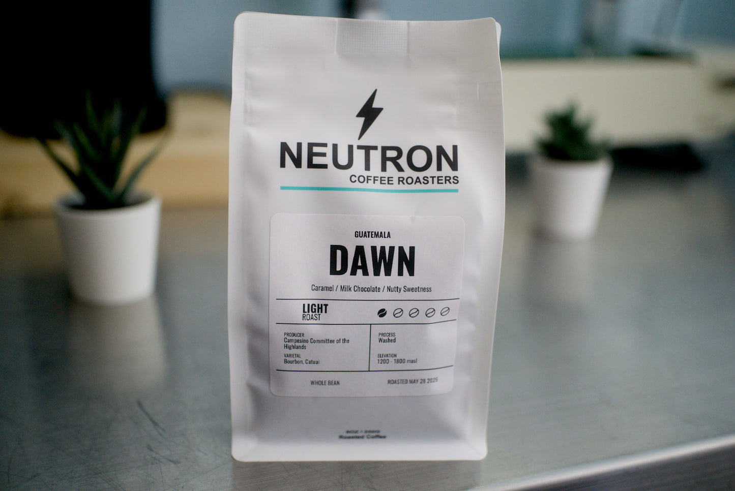 Neutron Coffee Roasters 'Dawn' coffee bag on a metal surface with a blurred background.