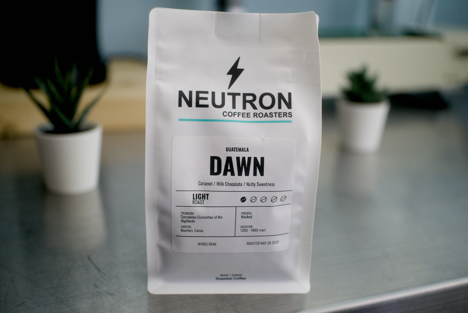 Neutron Coffee Roasters 'Dawn' coffee bag on a metal surface with a blurred background.
